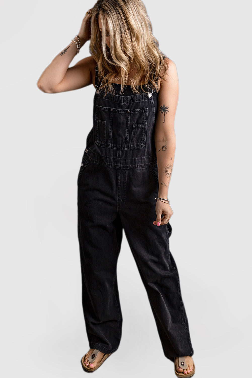 Black denim jumpsuit with adjustable buckle straps and multiple pockets