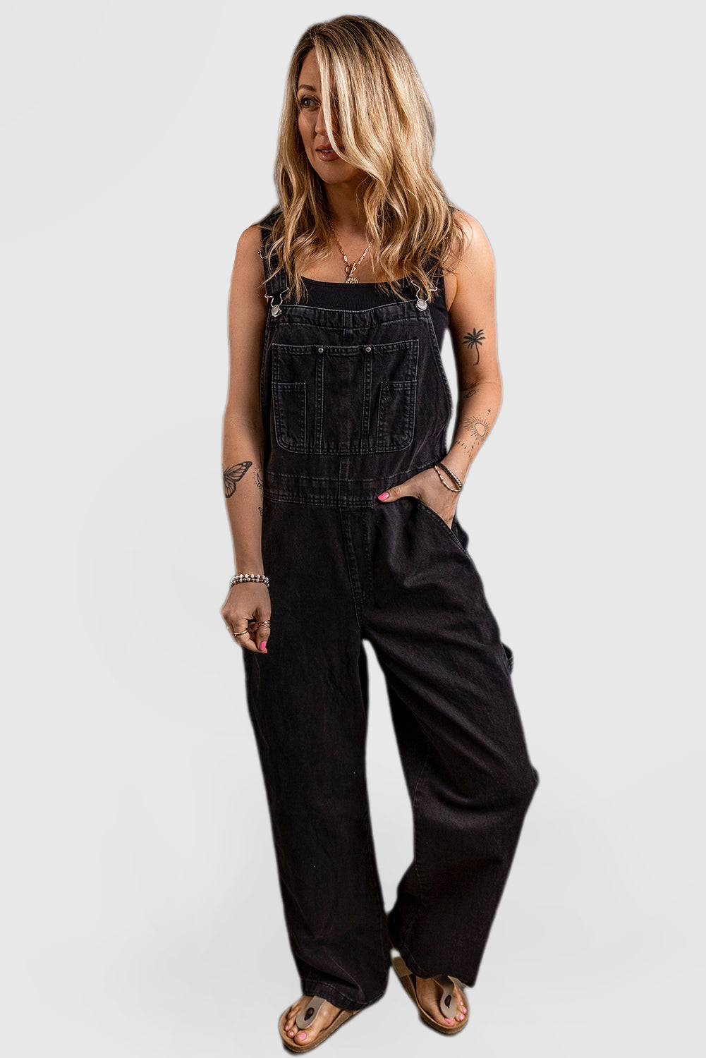 Black denim jumpsuit with adjustable buckle straps and multiple pockets