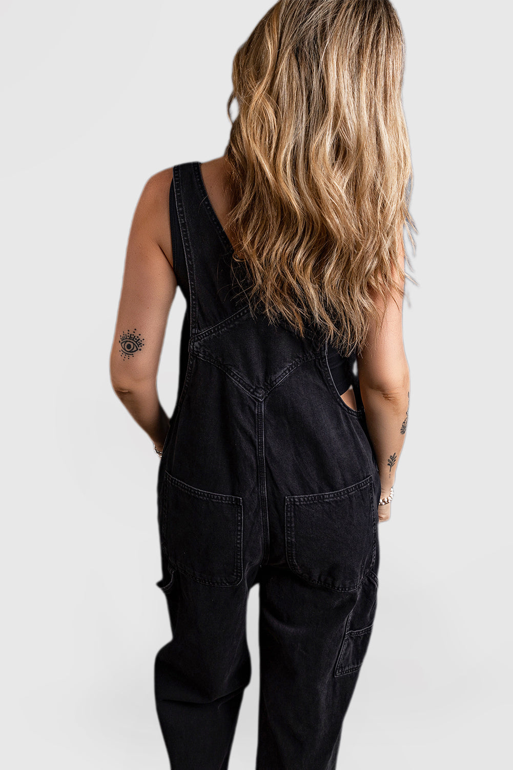 Black denim jumpsuit with adjustable buckle straps and multiple pockets
