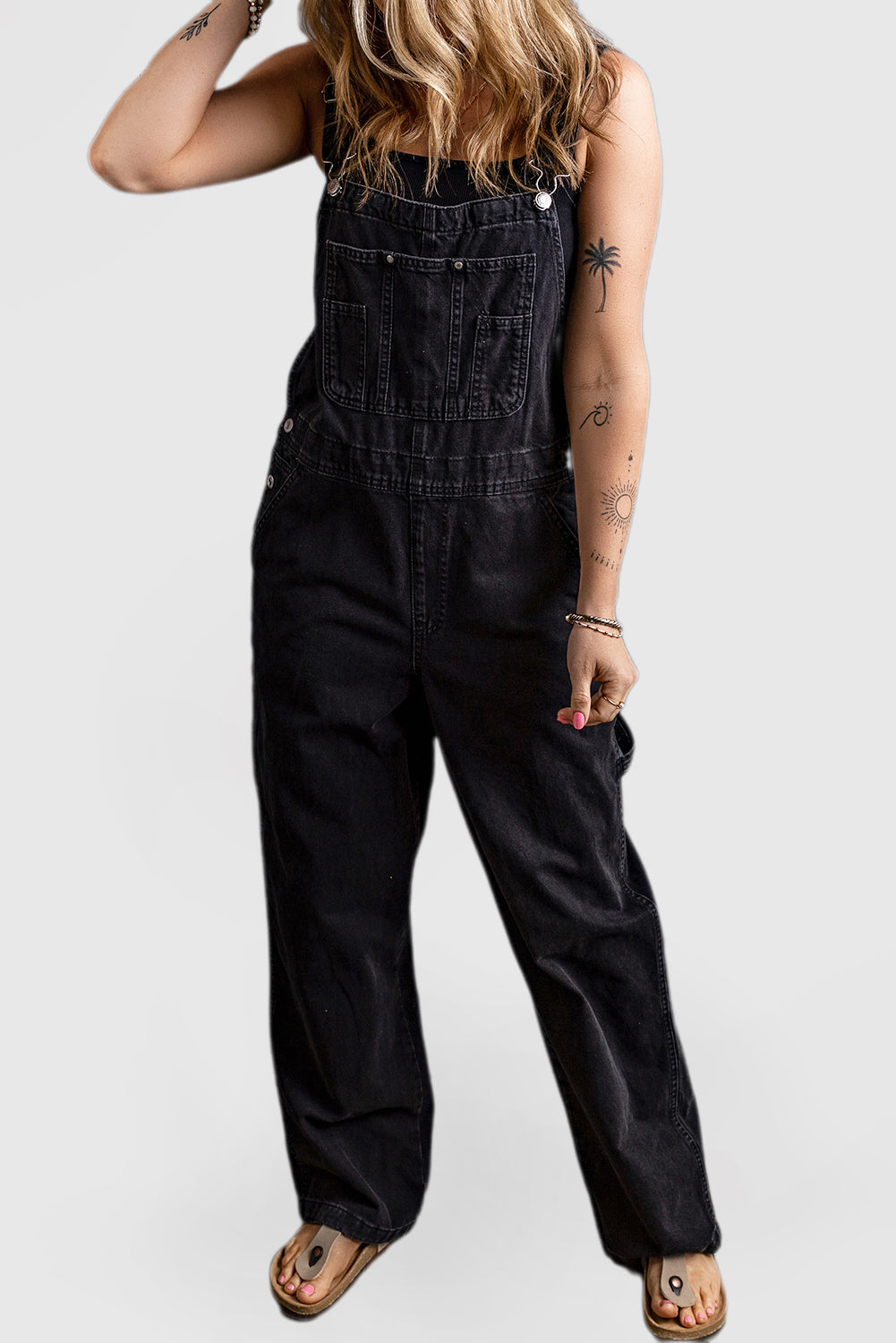 Black denim jumpsuit with adjustable buckle straps and multiple pockets