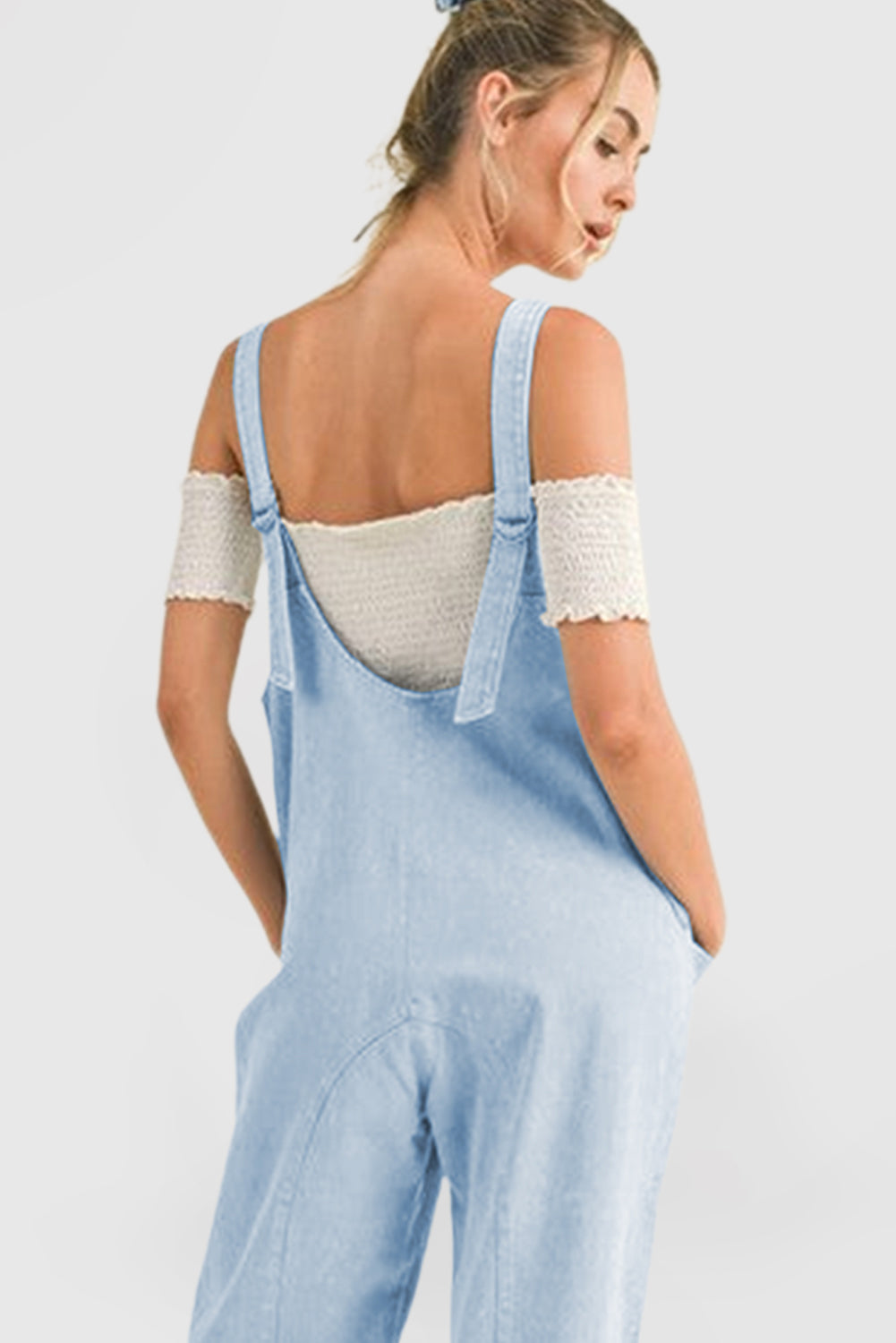 Blue V-neck denim jumpsuit with adjustable straps and pockets