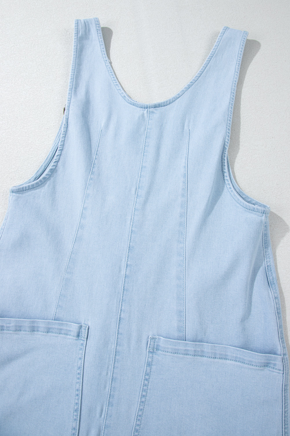 Blue V-neck denim jumpsuit with adjustable straps and pockets