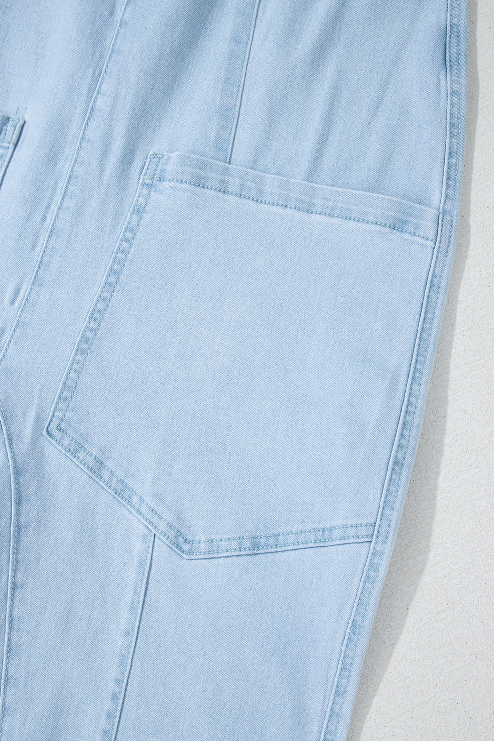 Blue V-neck denim jumpsuit with adjustable straps and pockets