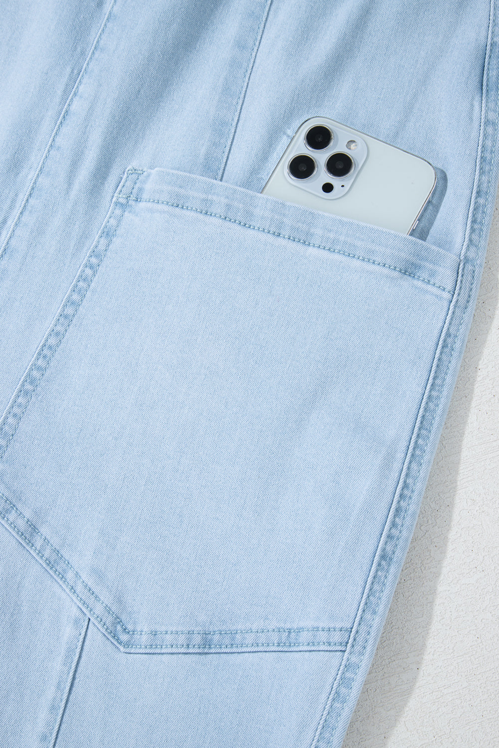 Blue V-neck denim jumpsuit with adjustable straps and pockets